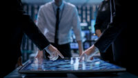 Business professionals engaged in corporate decision making, analyzing data on a digital touchscreen in a modern office setting.
