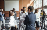 People networking at a professional event representing small business owner peer groups, discussing growth strategies and business insights.